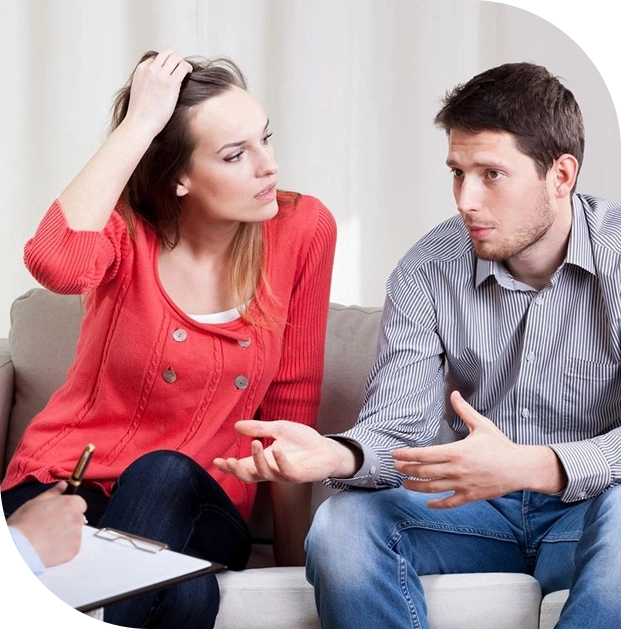 A man and woman sitting on the couch talking to each other.