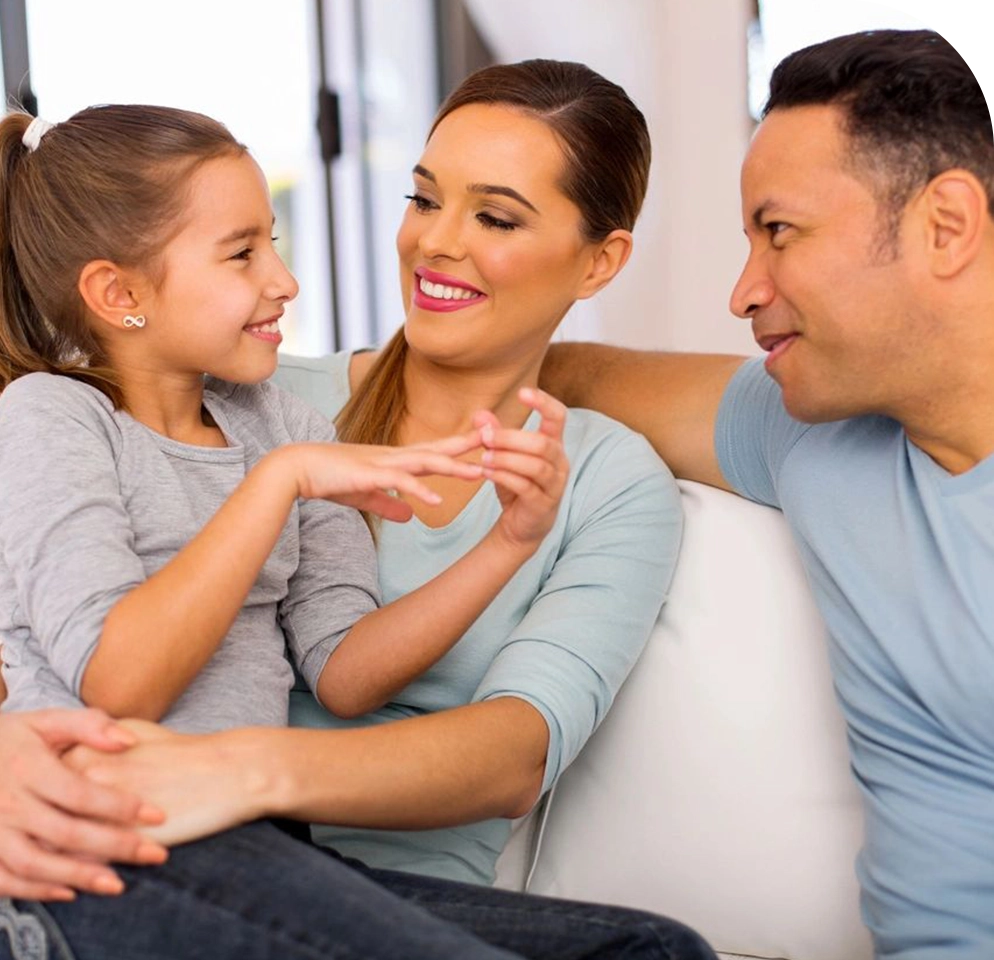 A family sitting on the couch together and smiling.