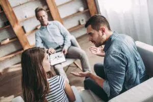 A group of people sitting around talking to each other.