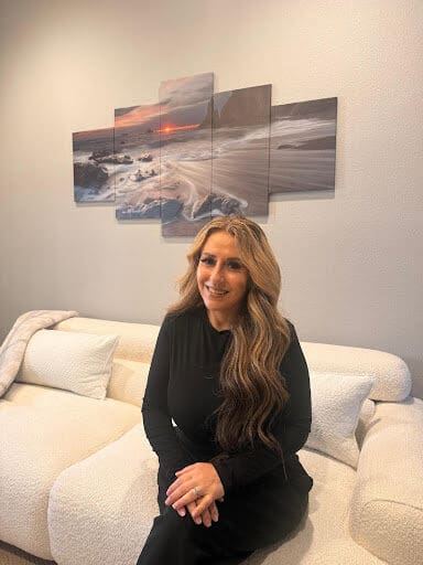 Woman sitting on couch with coastal wall art