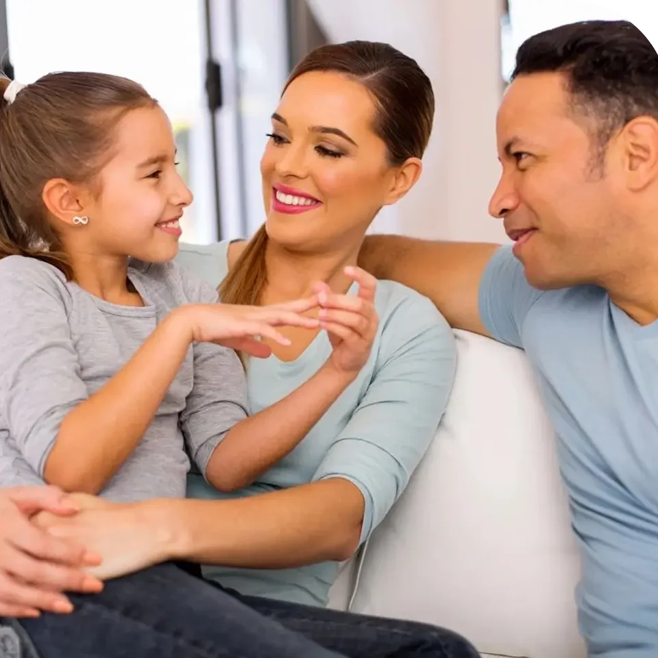 A family sitting on the couch together and smiling.