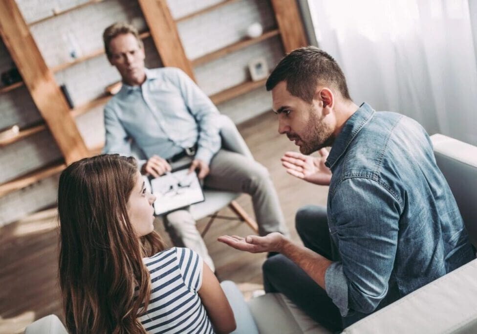 A group of people sitting around talking to each other.